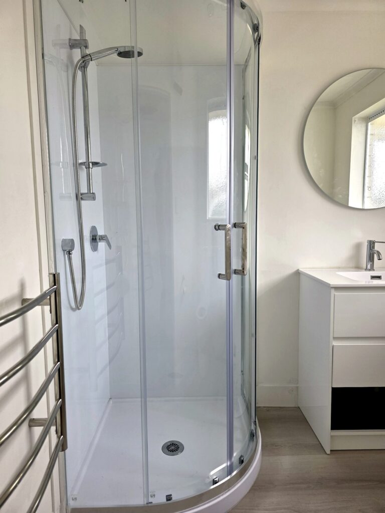 Finished bathroom with curved glass shower and vanity